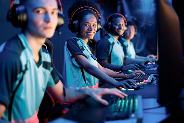 Selective focus on African female gamer looking at camera and smiling while using computer for online game in cyber club